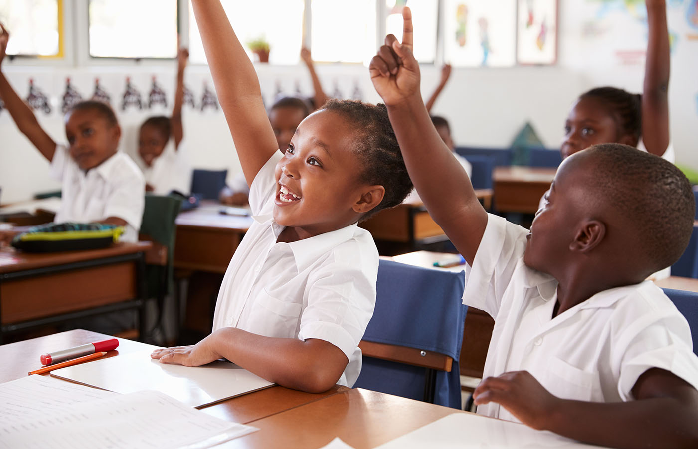Ghanaian schoolchildren raising their hands in class