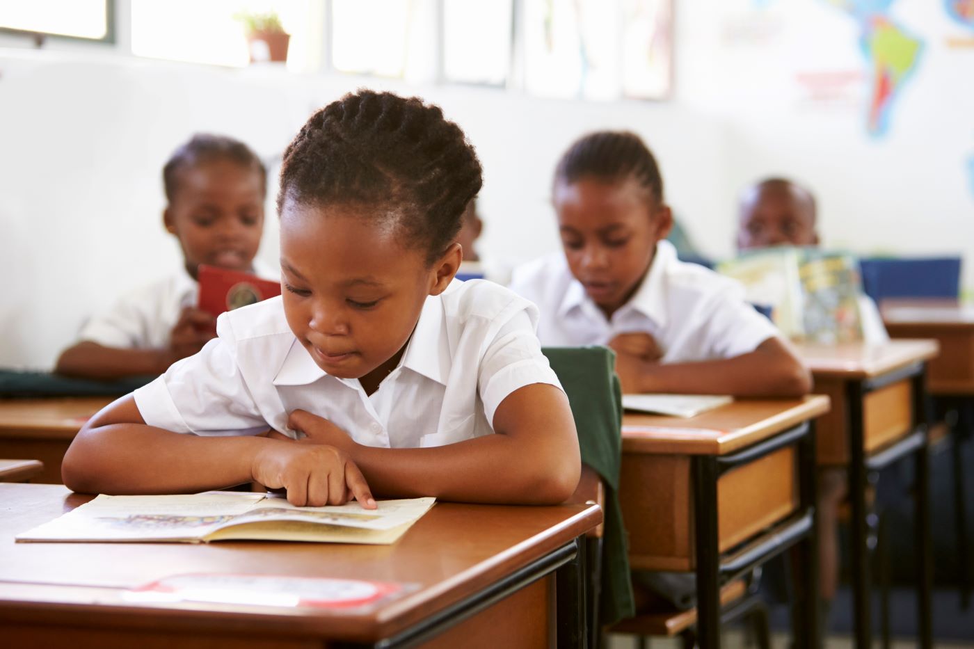 A pupil reading at her desk alongside classmates