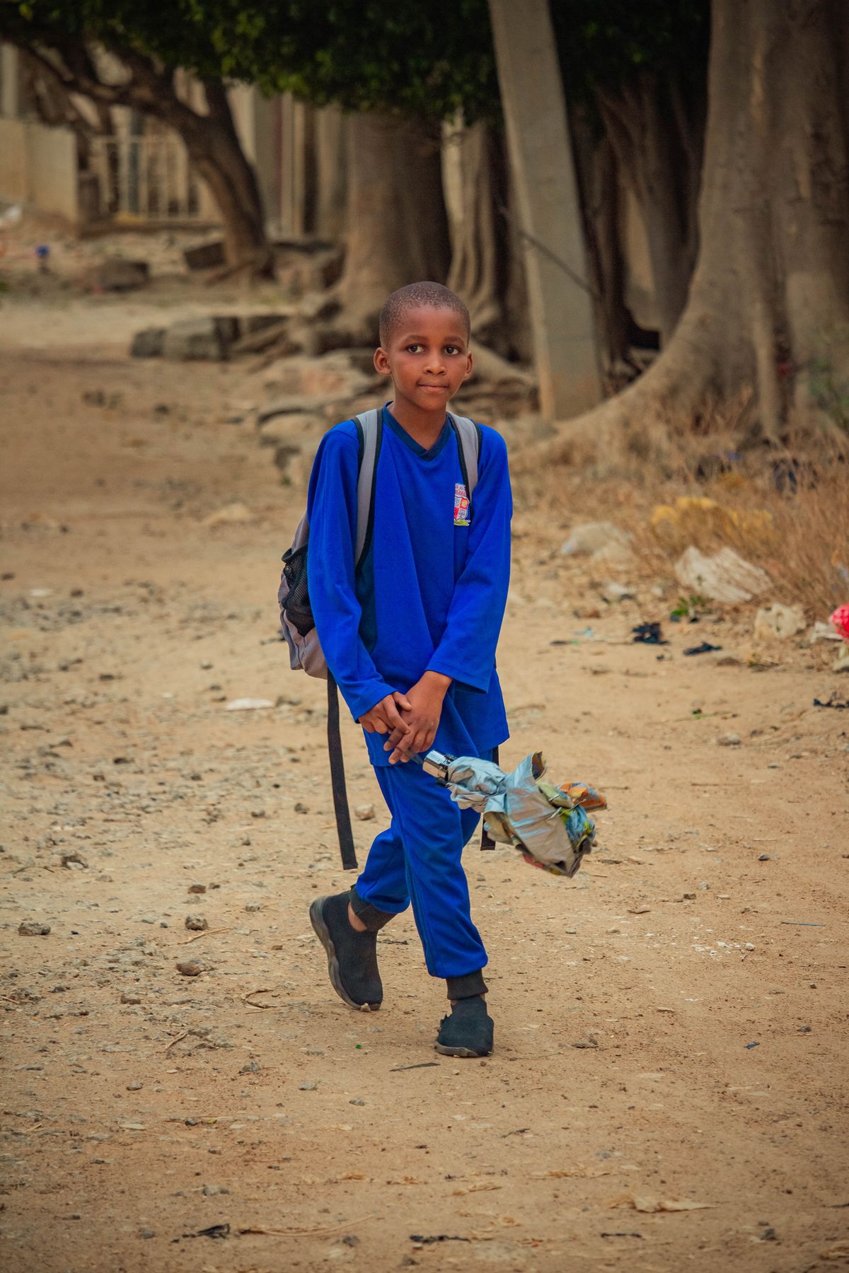 A boy walking home from school carrying his backpack